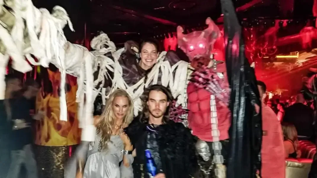 Stilt performers in mummy and demon costumes in a red-lit nightclub
