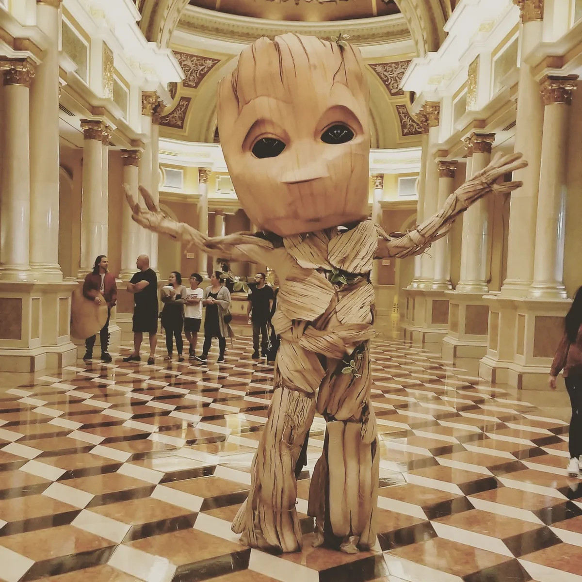 A giant Groot costume posing in a marble casino hall